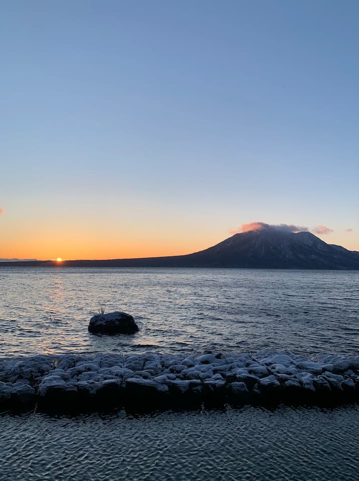 Soaking in the hot spring while witnessing the breathtaking sunrise over Lake Shikotsu at Marukoma Hot Spring Hotel