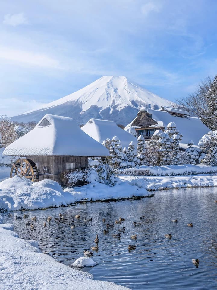 Crystal-clear pond in Oshino Hakkai reflecting the majestic Mount Fuji, surrounded by traditional Japanese houses.