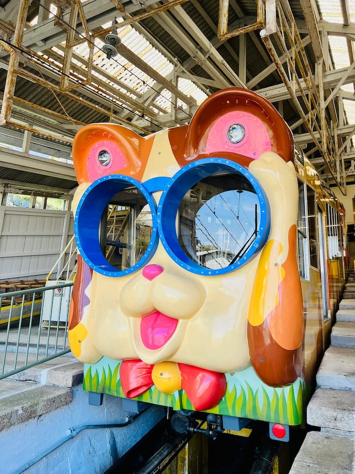 A doggy-themed cable car on the Ikoma Cable Car route, featuring a charming puppy design against a scenic mountainous backdrop