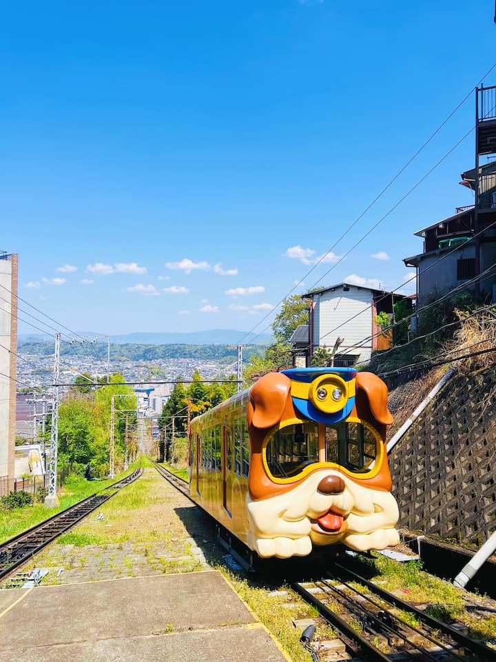 A doggy-themed cable car on the Ikoma Cable Car route, featuring a charming puppy design against a scenic mountainous backdrop