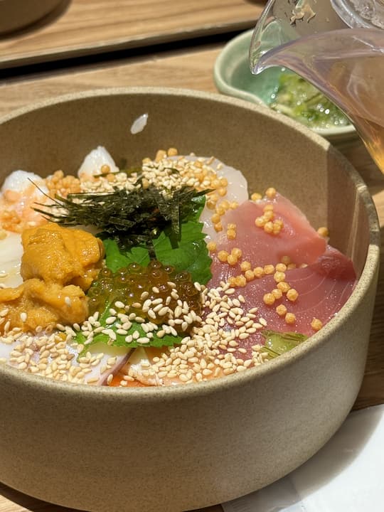 Seafood ochazuke at Kyoto Obuya near Kyoto Station, with fresh sashimi and steaming hot broth poured over rice, creating a fragrant and flavorful dish.