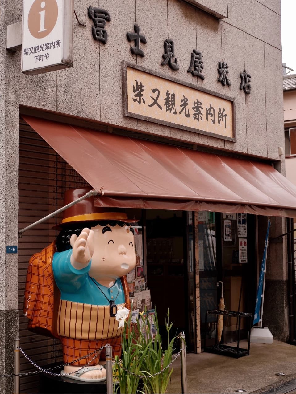 Retro-style shops and buildings along a bustling street in Shibamata, showcasing unique merchandise and traditional Japanese snacks