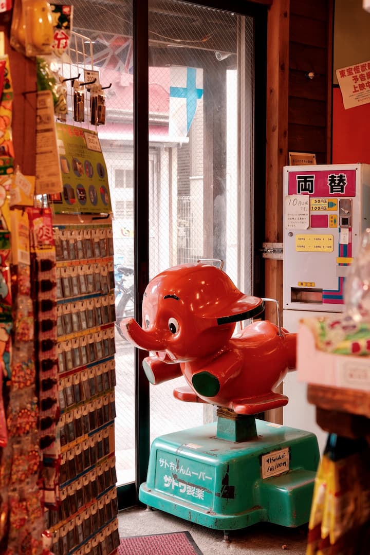 Retro-style shops and buildings along a bustling street in Shibamata, showcasing unique merchandise and traditional Japanese snacks